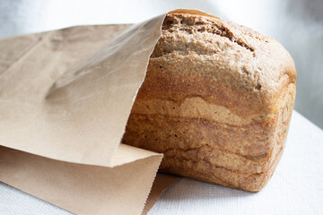 Closeup of freshly baked homemade traditional wheat sourdough bread in a craft bag. Selective focus. Concept - Cooking at Home