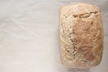 Freshly baked wheat homemade bread on craft paper, with place for your text, top view.