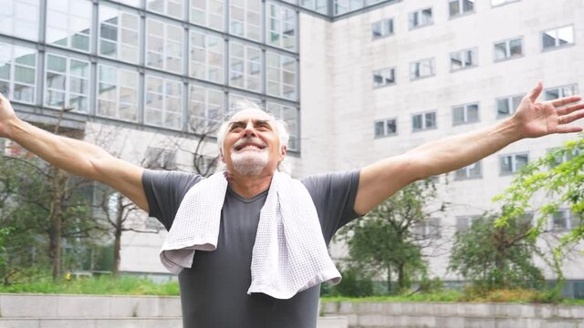 Slow motion shot of smiling senior athletic man with arms raised