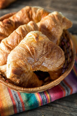 Warm croissant in a wicker basket with colourful napkin