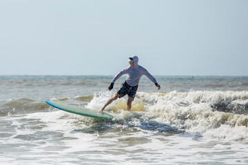 Middle aged man surfing on a long board in the Atlantic Ocean.