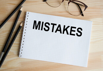 The word error is written on a white notebook, next to pencils and glasses, on a wooden background.