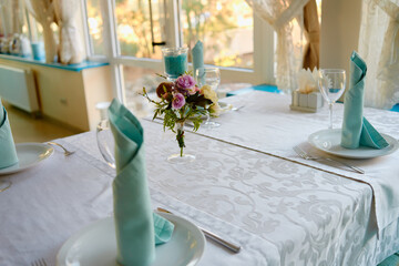 Floral arrangement of rose flowers and greenery in vase on wedding table in restaurant, copy space. Luxury wedding decorations. Table setting