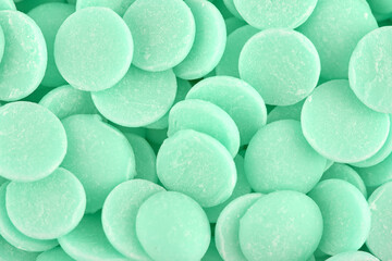 Green candy chocolate background, copy space. Closeup of pile chocolate drops candies. Candy texture. Candy pattern. Sweets background. Top view, flat lay