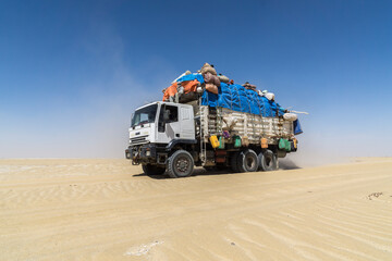 Heavily loaded truck transporting goods and people in the Sahara desert, Chad