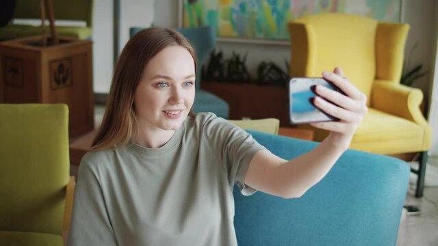 Happy young woman making facetime video chat calling with smartphone at home, using zoom conference meeting online app, social distancing, work from home, work remotely concept