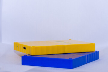 Yellow and blue portable usb hardrives stacked on isolated white background.