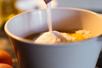 Detailed view of yeast falling into a bowl to prepare a cooking recipe. Preparation of a homemade cake at home.