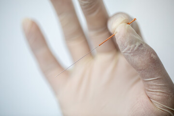The doctor's hand in glove with needle for acupuncture