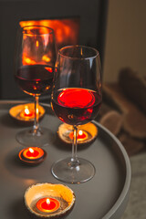 Two glasses of red wine front of fireplace. Romantic light