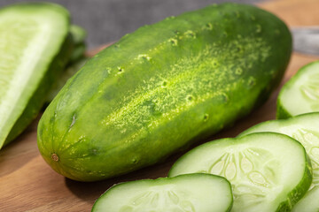 Organic Cucumber and slices on wooden cutting board. Cucumis sativus
