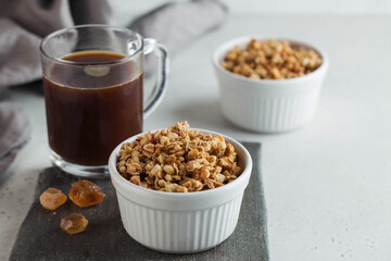 Homemade granola in a white bowl with caramel and a Cup of coffee. The concept of a healthy Breakfast. Copy space.