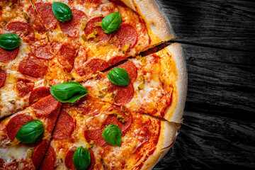 Pepperoni Pizza with Mozzarella cheese, salami, Tomato sauce, pepper, Spices and Fresh basil. Italian pizza on wooden table background