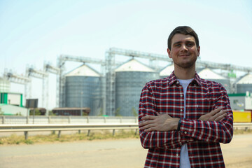 Young man against grain silos. Agriculture business © Atlas