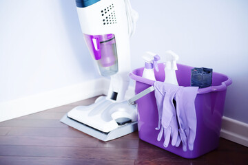 Bucket with cleaning supplies collection. Purple background. Housework concept. Cleaning service. Steam mop cleaner.