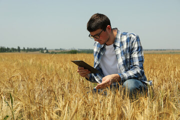 Young man with clipboard in barley field. Agriculture business