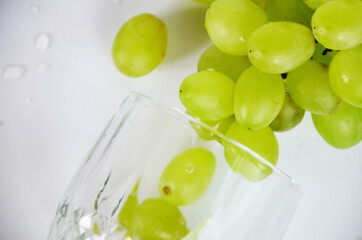 white grapes in a wine glass. White wine in a glass with fall grapes, white background, selective focus