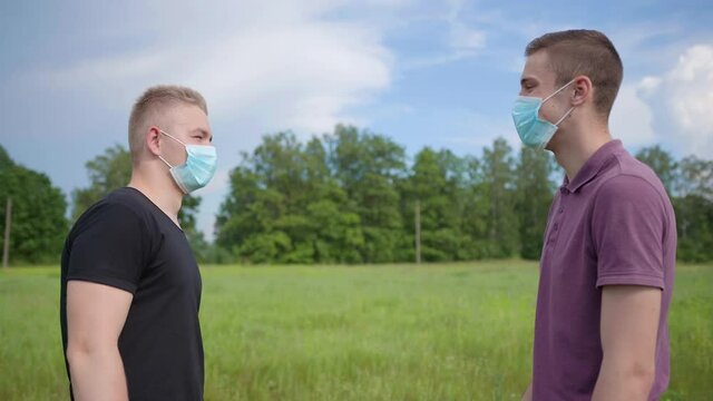Two masked friends greet each other with logs. The concept of greeting during the pandemic.