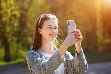 A happy woman communicates online on a smartphone in a Park