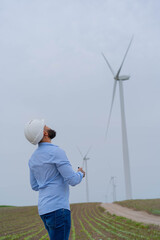 Engineer inspecting wind mill. Flying drone in wind park.