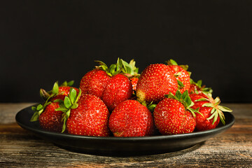 Strawberries on a plate on a wooden surface.