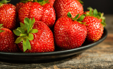 Strawberries on a plate on a wooden surface.