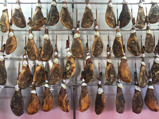 Jamon - spanish national delicacy, presented in showcase in the market. The hamon hangs in rows for sale. Spain.