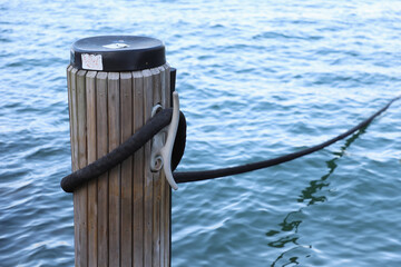 Wooden mooring post with metal hook and rope