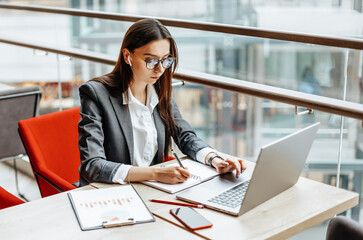 Girl works on a laptop in the workplace. Successful business woman creates a startup and makes decisions.