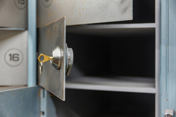 Open empty deposit box with a key in the lock. Bank depository
