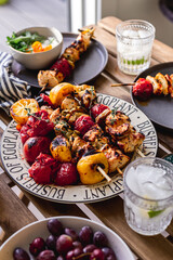 Grilled chicken breast and vegetables skewers. Barbeque summer time. Party dinner. Table setting. Bright and vibrant colors. Charred veggies. Picnic scene. Lemon, artichokes, tomatoes. Weekend grill