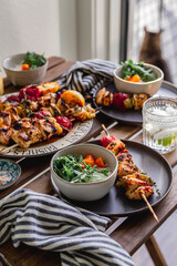 Grilled chicken breast and vegetables skewers. Barbeque summer time. Party dinner. Table setting. Bright and vibrant colors. Charred veggies. Picnic scene. Lemon, artichokes, tomatoes. Weekend grill