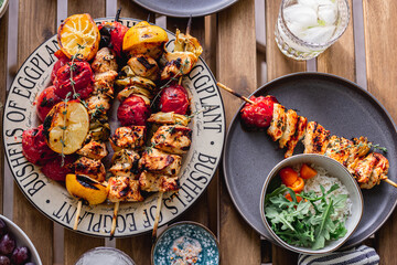 Grilled chicken breast and vegetables skewers. Barbeque summer time. Party dinner. Table setting. Bright and vibrant colors. Charred veggies. Picnic scene. Lemon, artichokes, tomatoes. Weekend grill