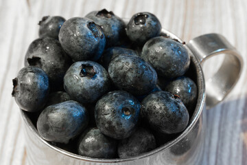 Fresh blueberries in a metal bowl on a wooden board
