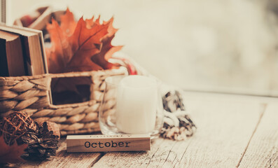 Details of still life on window. Basket of books and autumn leaves on wood background. Autumn mood.