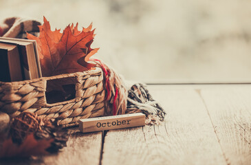 Details of still life on window. Basket of books and autumn leaves on wood background. Autumn mood.