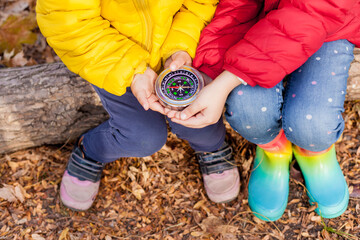 Girls Toddler holding compass in the hands. Children exploring nature in the forest on warm autumn...