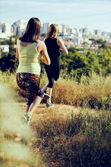 Two pregnant young women practicing yoga outdoors.