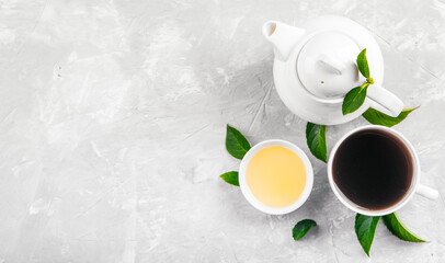 Herbal tea, cups and teapot with leaves on grey concrete background. Flat lay.