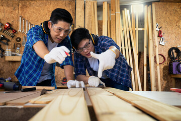 Carpenter measuring And cut wood to make furniture. Two carpenters are working in a wood factory.