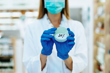 Female pharmacist with protective mask on her face working at pharmacy. Medical healthcare concept. Discount, sale concept.