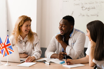 Online multiethnic attractive group of teachers study and laught, discuss something. Remote work in multinational group with laptop. Happy girls and black man speaking online by laptop