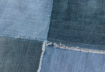 Old denim jeans texture or background made from different colored jeans peaces.