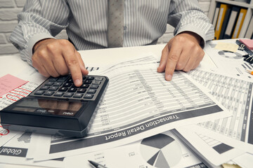 Business analysis and accounting concept - businessman working with document, spreadsheet, using calculator, tablet pc. Office desk closeup.