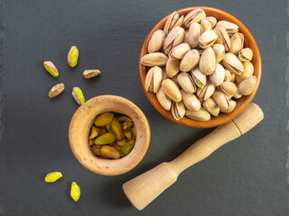 Still life of pistachio. Homemade pistachio grain with mortar and pestle. Traditional Italian cuisine. Pistachios with shell, without shell and crushed. Dark background.