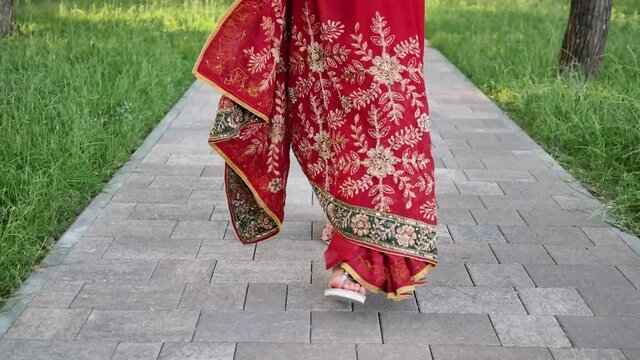Close up of legs of young woman in Indian saree walking in the Park