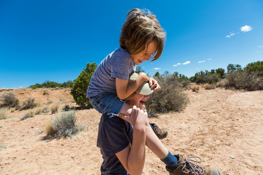 14 year old girl giving younger brother a piggyback ride, Galisteo Basin, NM.