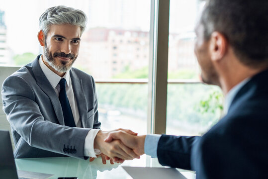 Businessmen shaking hands in office - Powered by Adobe