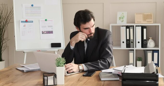 Thoughtful businessman coming up with a brilliant idea while working on laptop at office