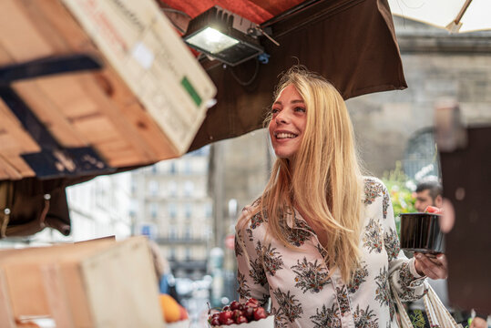 Young woman buying fruits at market stall
